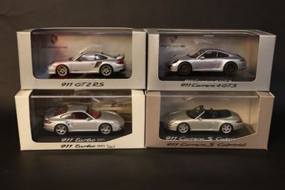 three silver porsche models in boxes on a black surface