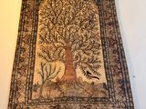 an old tapestry hanging on a wall with a tree and birds