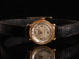 une image représentant une montre-bracelet dorée posée sur une surface noire