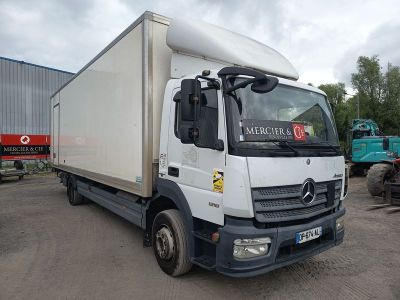 un camion blanc garé sur un parking, avec d'autres camions en arrière-plan