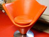 une chaise orange posée sur un sol rouge