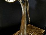 bronze sculpture of a woman holding a leaf on a black surface