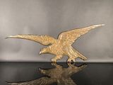 figurine d'un aigle royal posée sur une table noire, sur fond argenté
