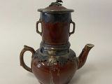 a brown tea pot with a lid on a white table