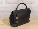 a black handbag sitting on top of a wooden table