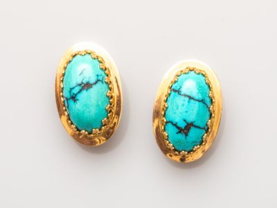 une paire de boucles d'oreilles en turquoise posées sur un fond blanc