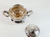 a silver bowl with a lid and a lid on a table