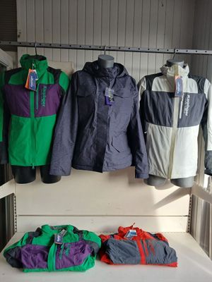 several jackets and bags are hanging on a rack in a room