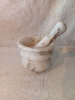 un mortier en marbre blanc et une cuillère en bois posés sur une table
