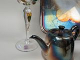 a tea pot sitting next to a wine glass on a table