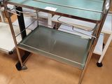 un chariot de service en métal et en verre au milieu d'une pièce