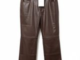 un pantalon en cuir marron suspendu à un cintre devant un mur blanc