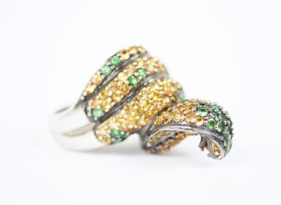 un gros plan d'une bague ornée de pierres vertes et jaunes
