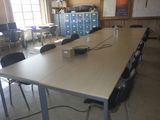 une longue table sur laquelle est posé un ordinateur portable, au milieu d'une pièce