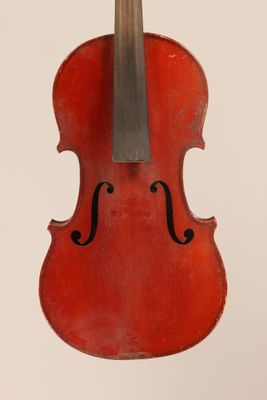 un vieux violon rouge posé sur une surface blanche