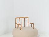 La chaise est en bois et est équipée d'un coussin beige.