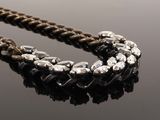 a close up of a necklace on a table with a black background