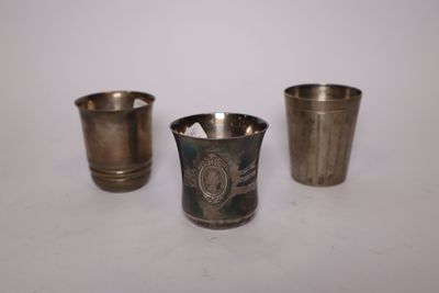three silver cups sitting next to each other on a white surface