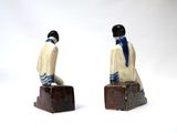 two figurines of a man and a woman sitting on suitcases