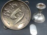 a silver plate with a bird on it next to a candle holder