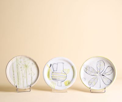 trois assiettes en céramique ornées de dessins représentant des toilettes, une cuvette de WC et une plante