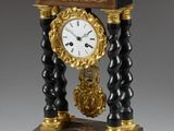 une horloge noire et dorée posée sur un socle, avec une clé