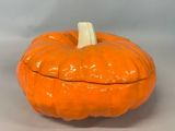une citrouille orange au sommet blanc, posée sur une table