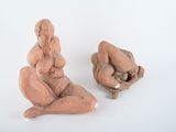 deux sculptures en argile représentant une femme et un homme, posées sur une surface blanche
