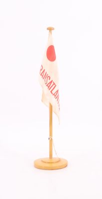 un petit drapeau sur un support en bois, sur fond blanc