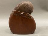 a brown vase with a ball of yarn in it