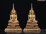 deux statues en or représentant des bouddhas assis sur un socle noir