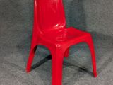 une chaise en plastique rouge posée sur une surface grise