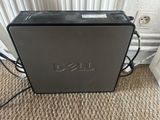 the dell desktop computer is sitting on the floor next to the wall