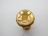 un gros plan d'une bague en or sur laquelle est gravé un blason