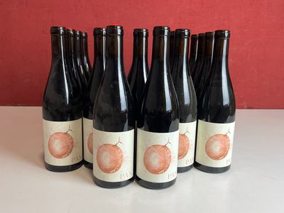 six bouteilles de vin posées sur une table près d'un mur rouge