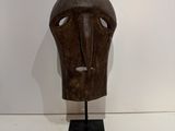 an image of a wooden mask on a stand on a white surface