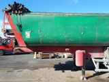 a green and red boat on a trailer in a parking lot