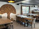 tables and chairs in a restaurant with a large tree on the wall