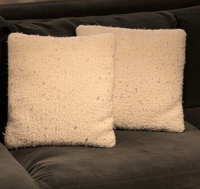 two white pillows sitting on top of a black couch next to each other