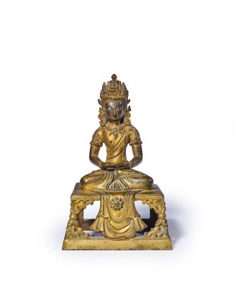 une statue en or représentant une personne assise sur un banc, sur fond blanc
