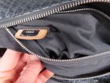 a person holding a black purse with a name tag