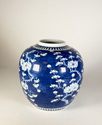 un vase bleu orné de fleurs blanches, posé sur une surface blanche