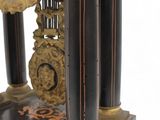 a black and gold clock on a stand on a white background