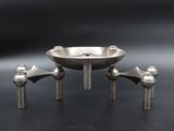 a metal bowl with two legs on a black surface
