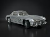 a silver toy car that is sitting on a black surface