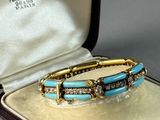 an image of a gold and turquoise bracelet in a case