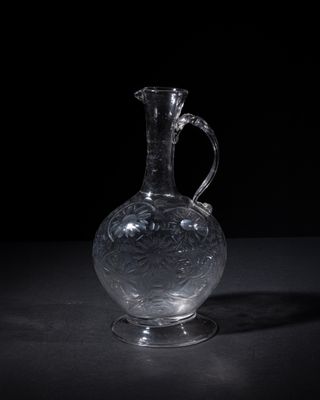 a clear glass vase with a handle on a table