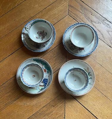 four small cups and saucers sitting on a wooden floor