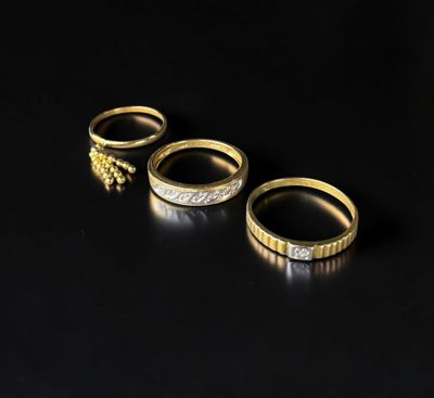 trois bagues en or serties de diamants sur fond noir