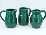 three green vases sitting next to each other on a white surface